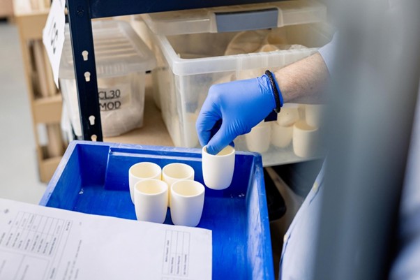 Worker selecting ceramic containers showing different types of crucible used in industrial material handling.